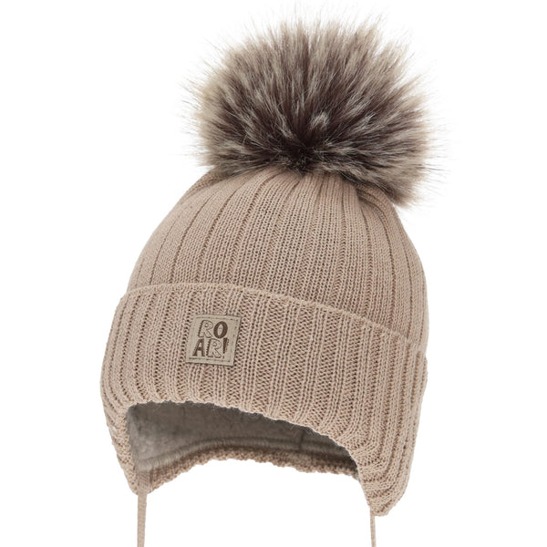 A beige knit hat with a fluffy pom pom on top, featuring a small patch on the front with the text "ROAR" printed on it.