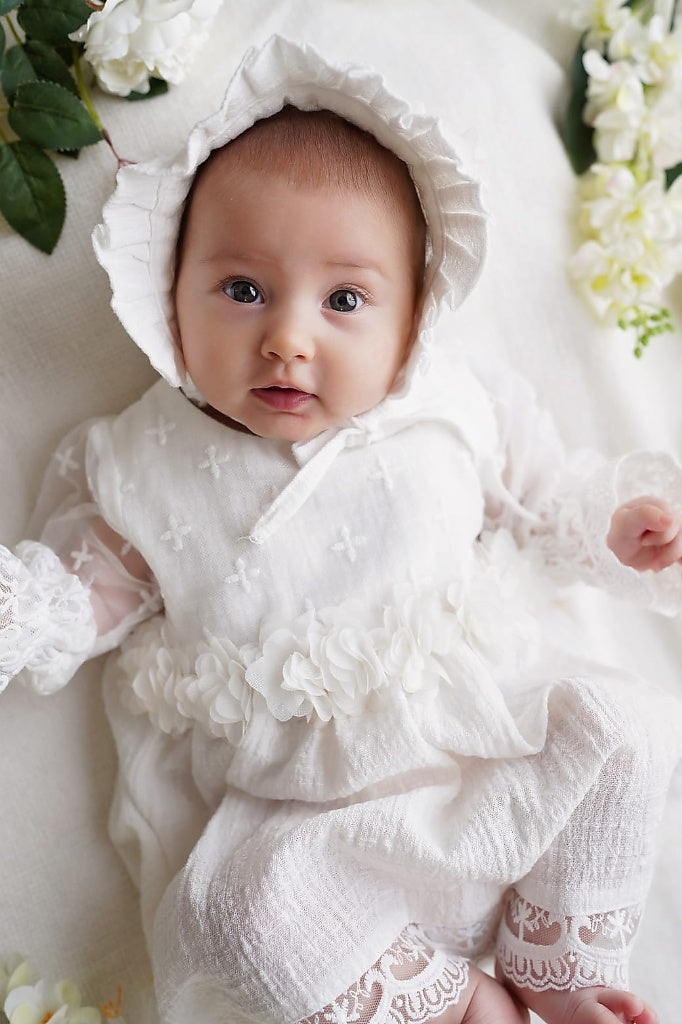 a baby wearing a white dress and bonnet