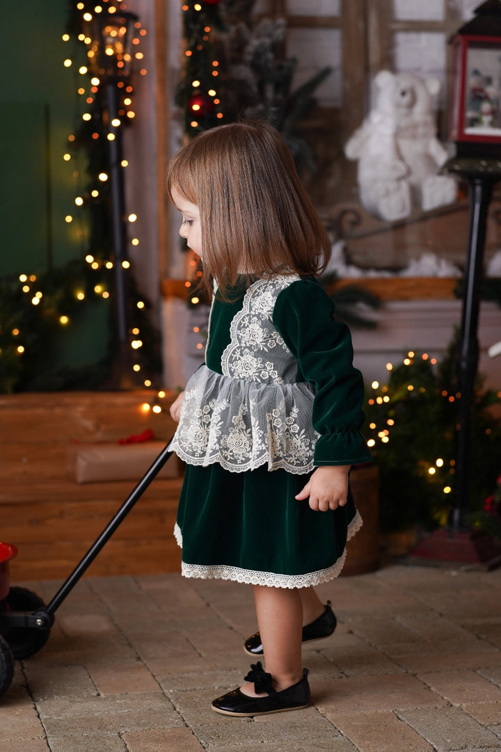 a little girl standing in front of a christmas tree