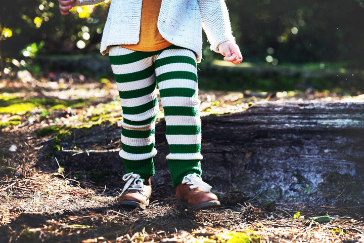 a little girl wearing green and white striped pants