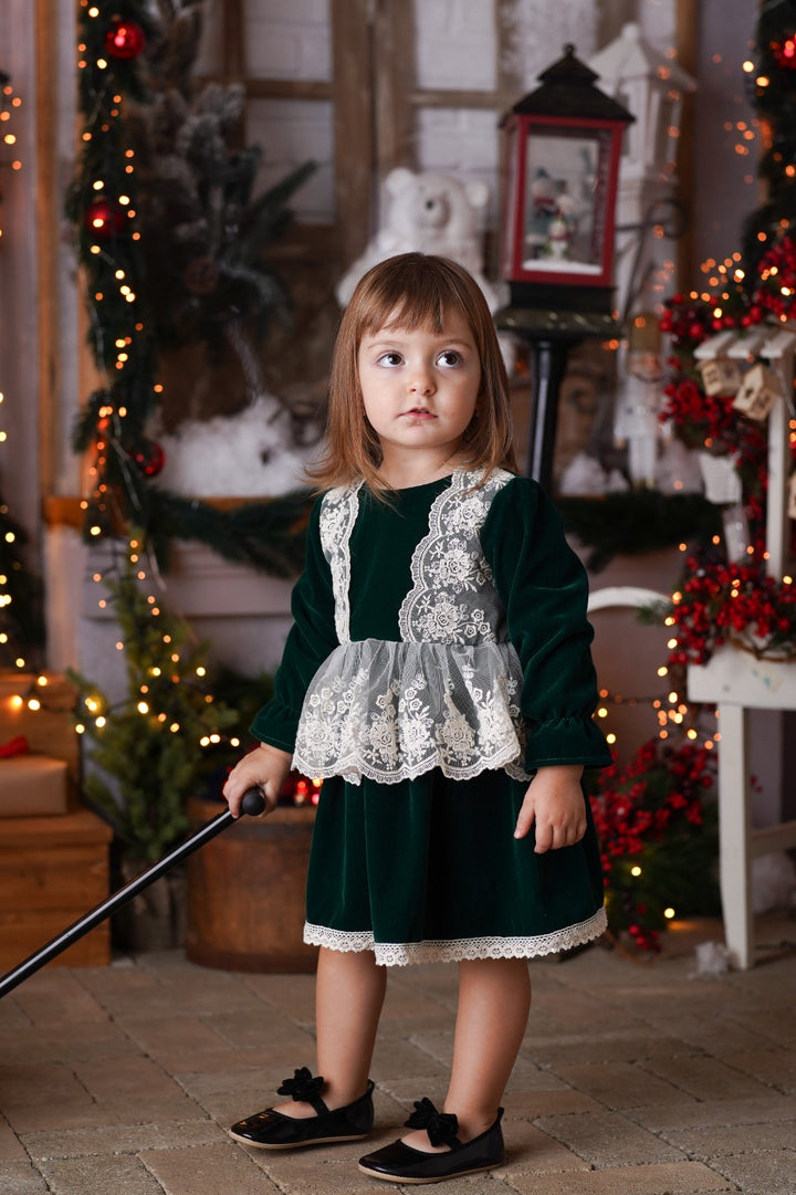 a little girl standing in front of a christmas tree