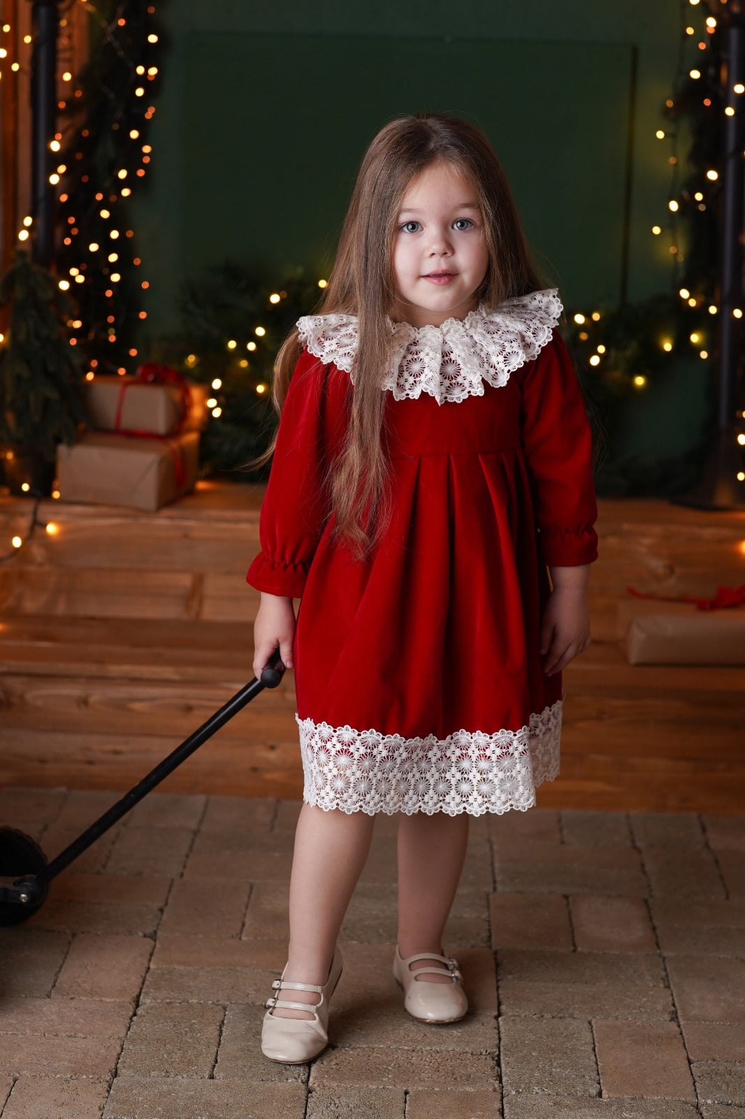 a little girl in a red dress holding a black stick