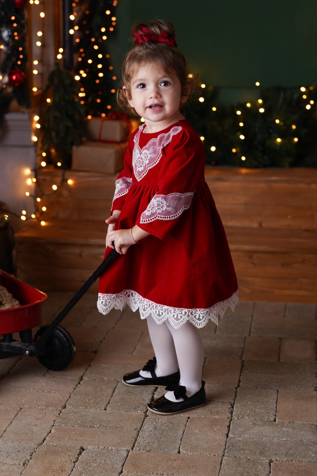 a little girl in a red dress holding a black stick