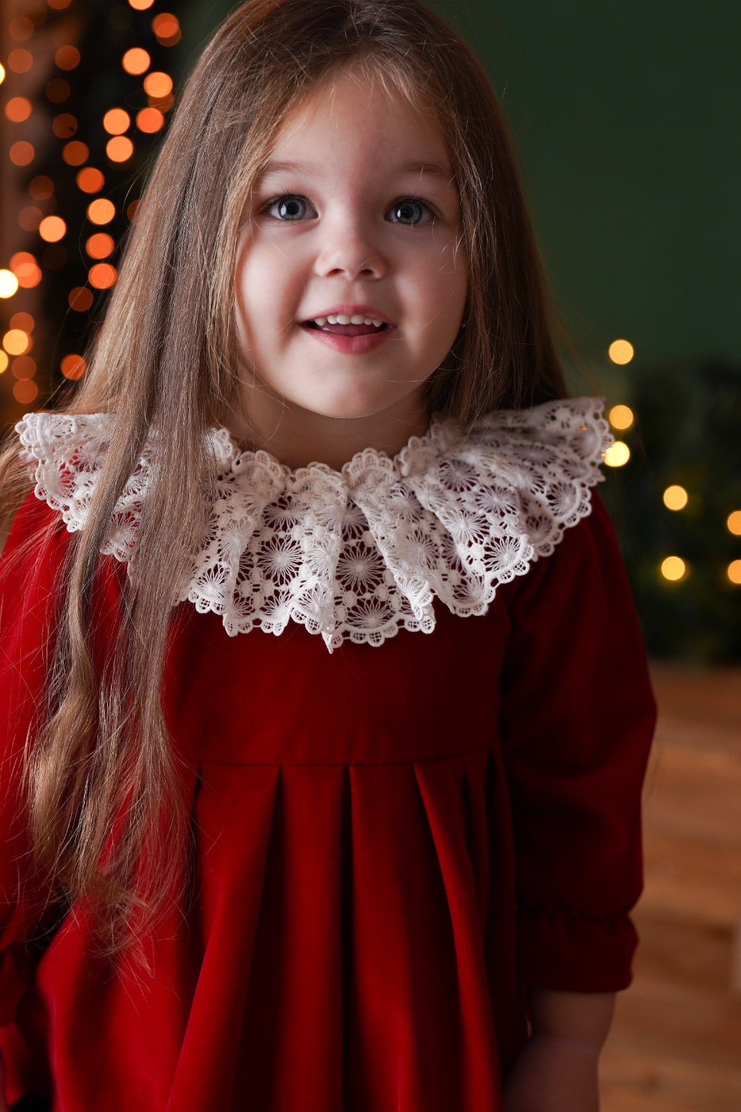 a little girl wearing a red dress and a white collar