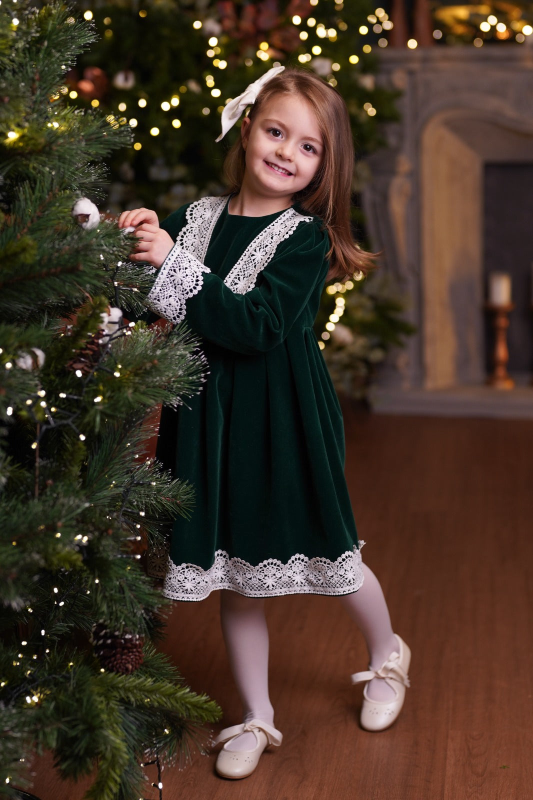 a little girl standing next to a christmas tree