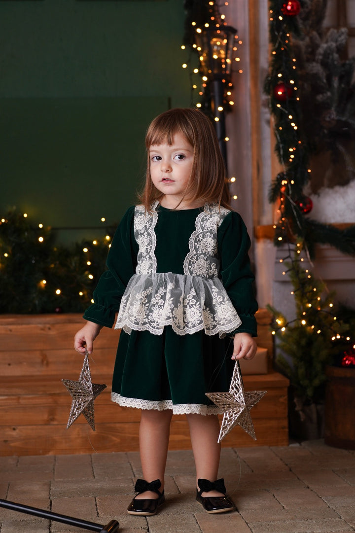 a little girl standing in front of a christmas tree