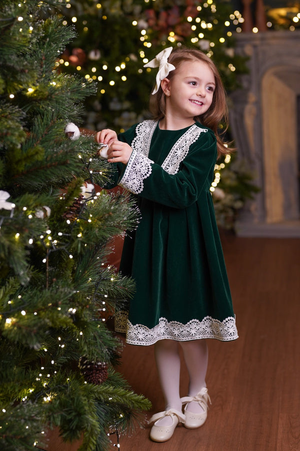 a little girl standing next to a christmas tree